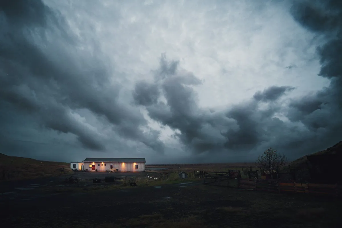 A house with its windows lit under a dark evening sky
